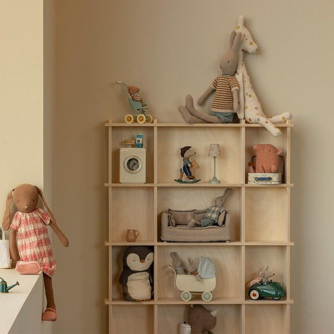 Wooden shelf with various toys and decorative items against a beige wall.