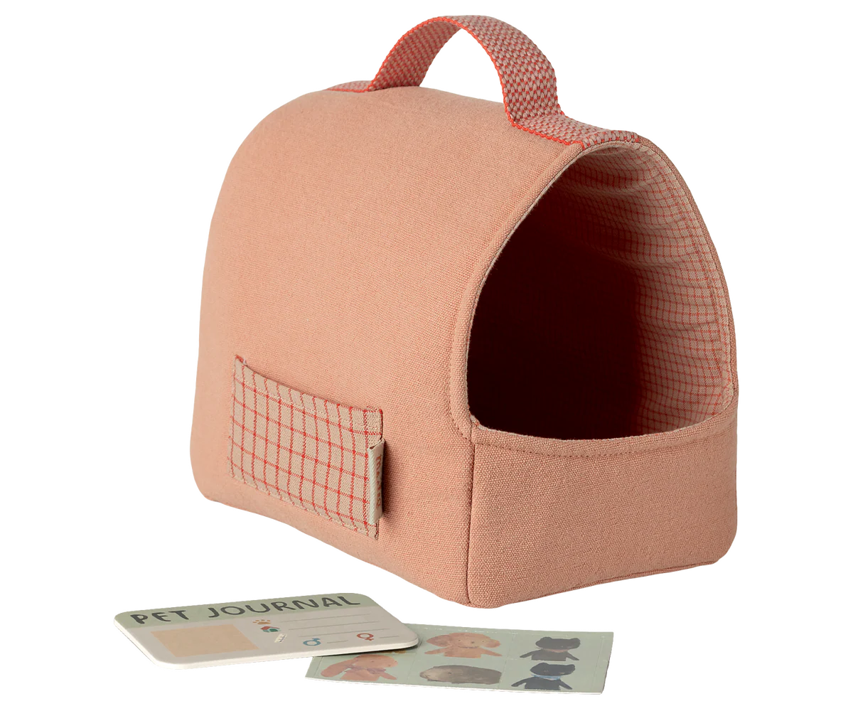 Pink pet carrier with a pet journal and cards on a white background