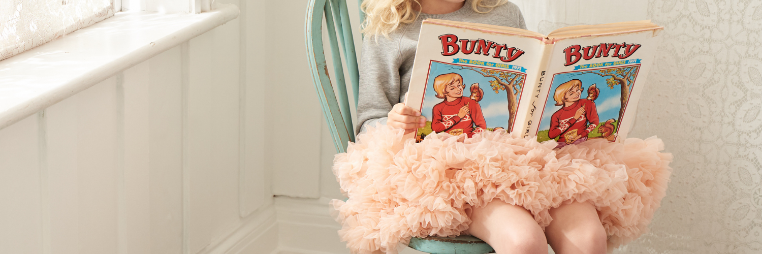 Girl wearing a pink Bob and Blossom tutu reading Bunty comic