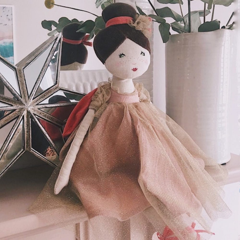 Moulin Roty Doll dressed in sparkly dress and fairy wings on a shelf with a star behind it
