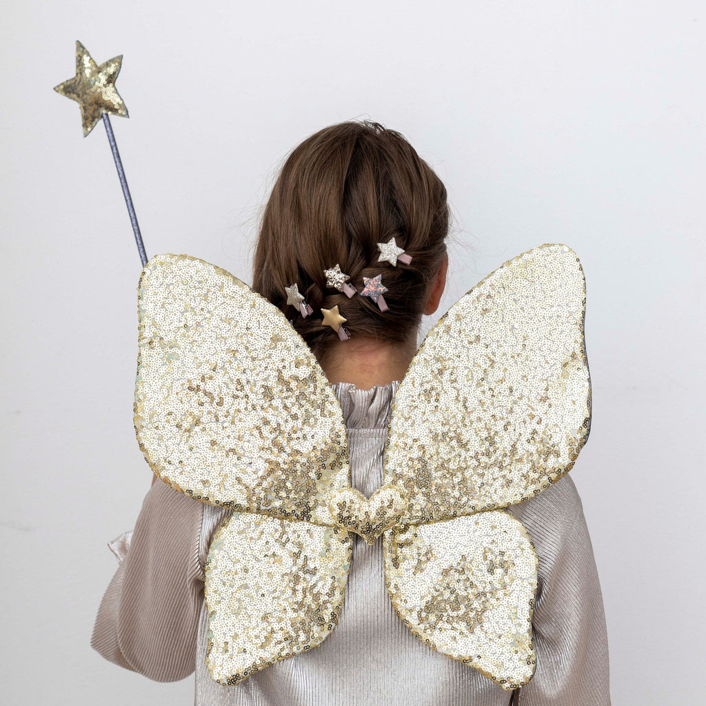 Girl wearing Mimi and Lula glittery fairy wings and holding a fairy wand