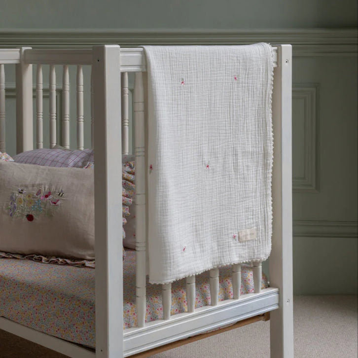 Avery Row Embroidered Muslin Blanket, Anemone Folded on cot