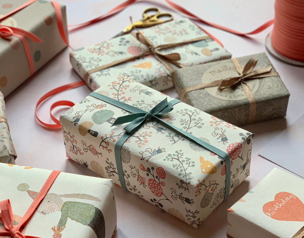 A selection of gifts wrapped in Maileg wrapping paper and ribbon in a table 