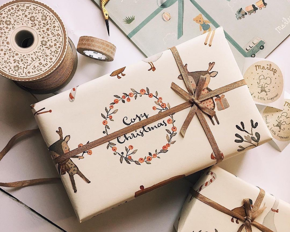 a wrapped present with the words cosy christmas on the front and wrapped with a gold bow