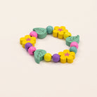 Colorful wooden teething toy with flowers and leaves on a beige background