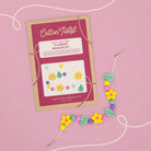 Cotton Twist flower bracelet kit with colorful beads on a pink background