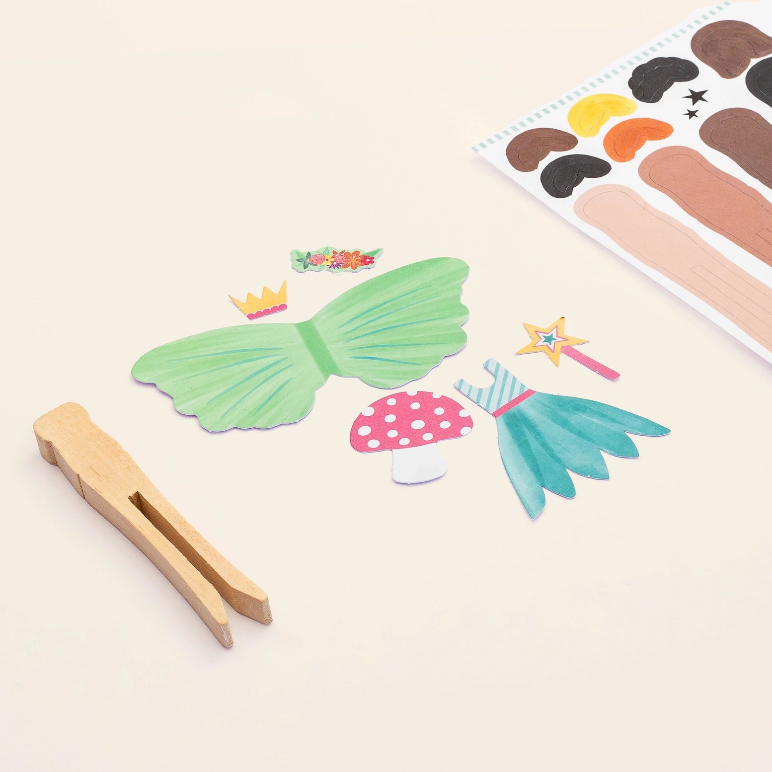 Colorful fairy-themed paper cutouts with a wooden clothespin on a light background