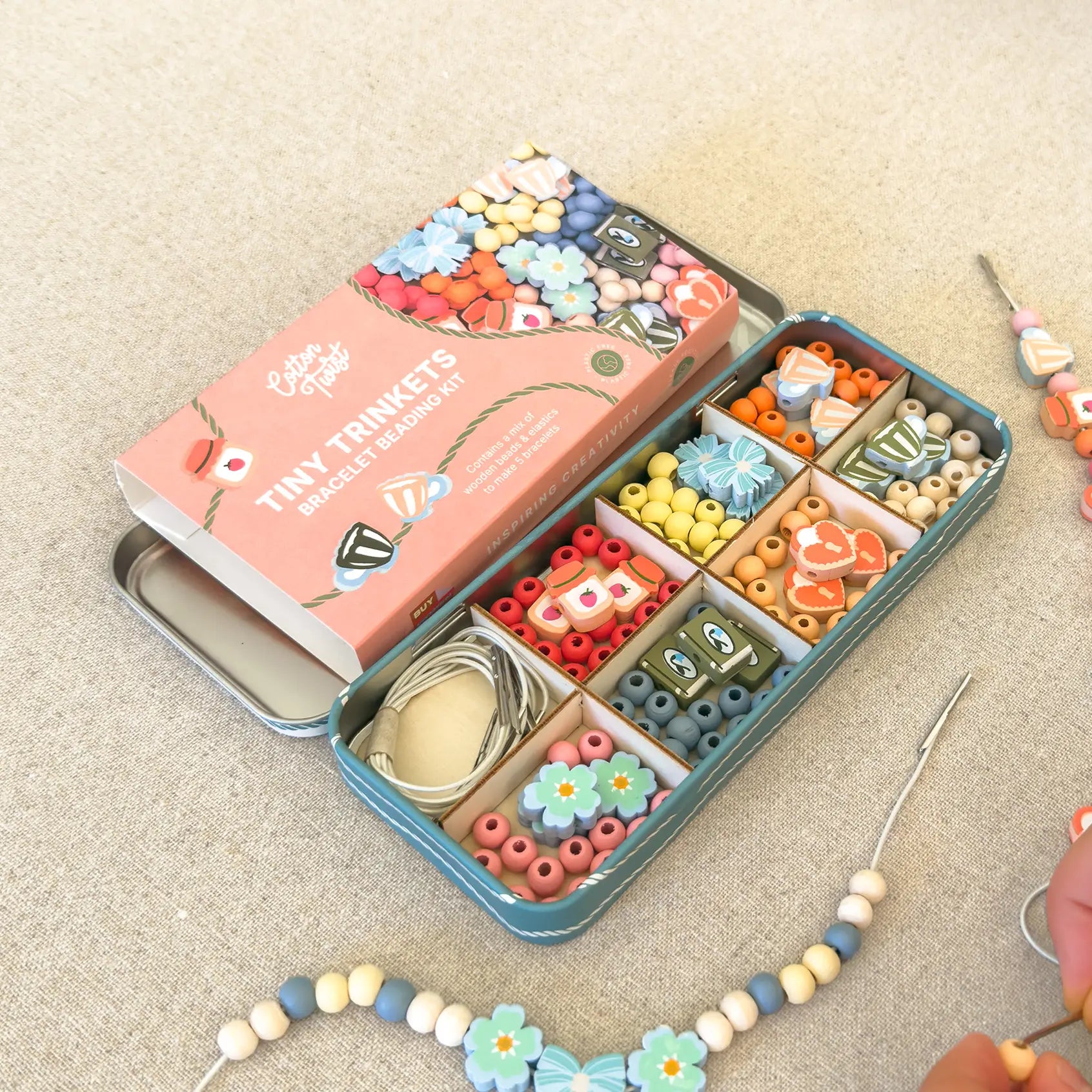 Bead kit with colorful beads and tools on a beige surface