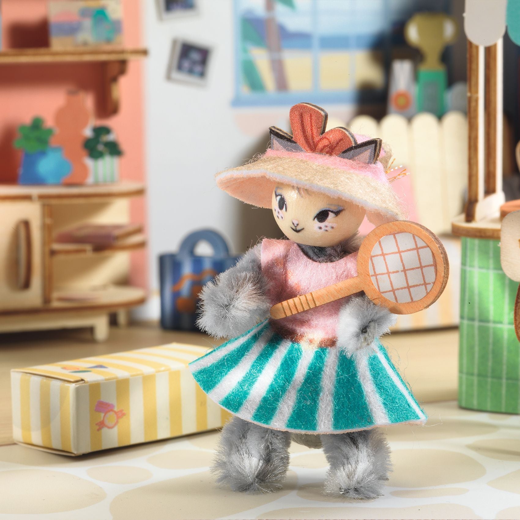 Toy figure of a character in a dress and hat holding a tennis racket in a room setting.