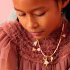 Close-up of a child wearing a pink ruffled dress with decorative ballerina themed jewelry.