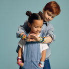 Two children wearing colorful watches on a plain background