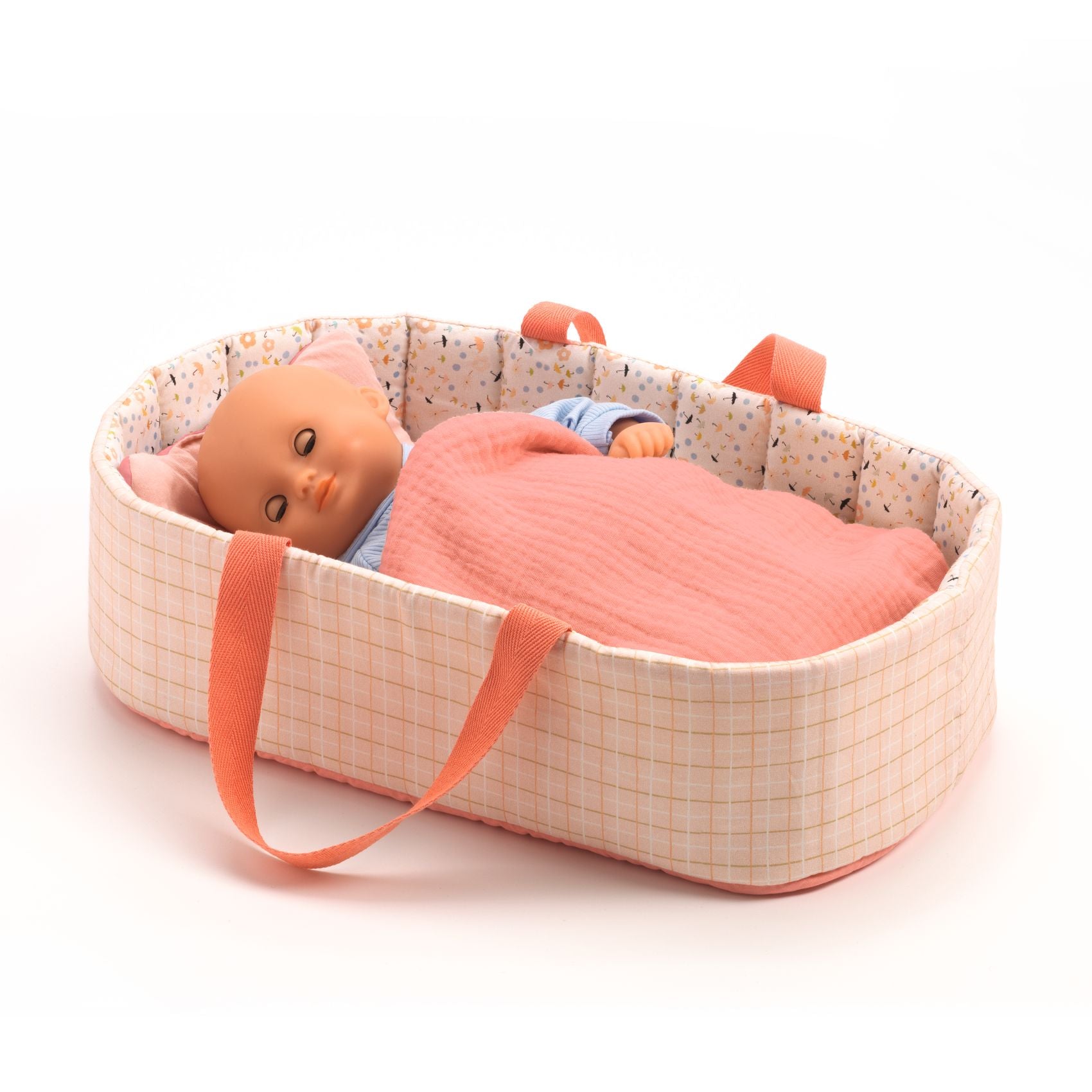 Baby doll in a portable crib with pink blanket on a white background