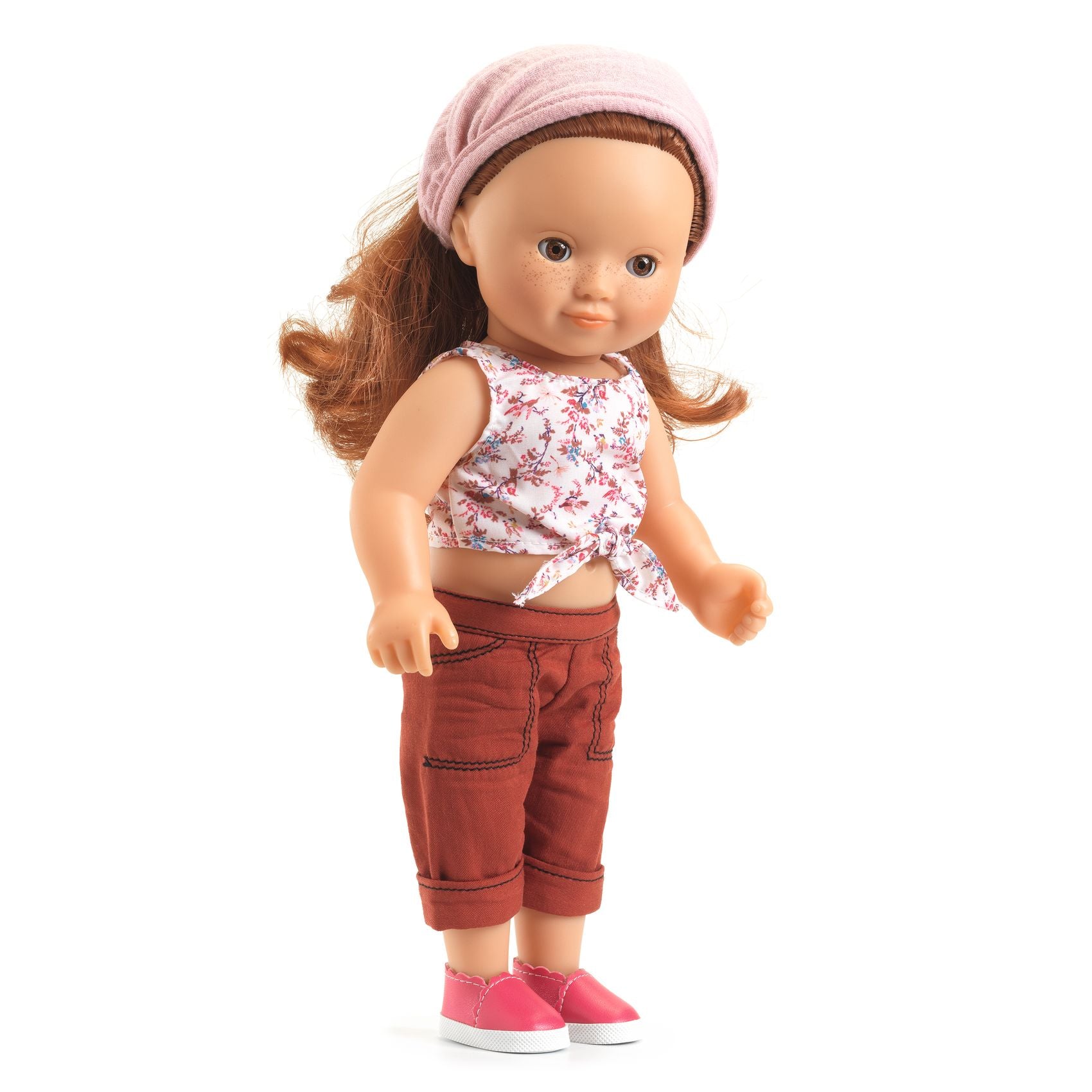 Doll wearing a floral top and brown pants with a pink headband on a white background