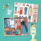 Set of paper dolls and clothing in a box on a green background