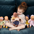 Child playing with a group of dolls on a blue couch