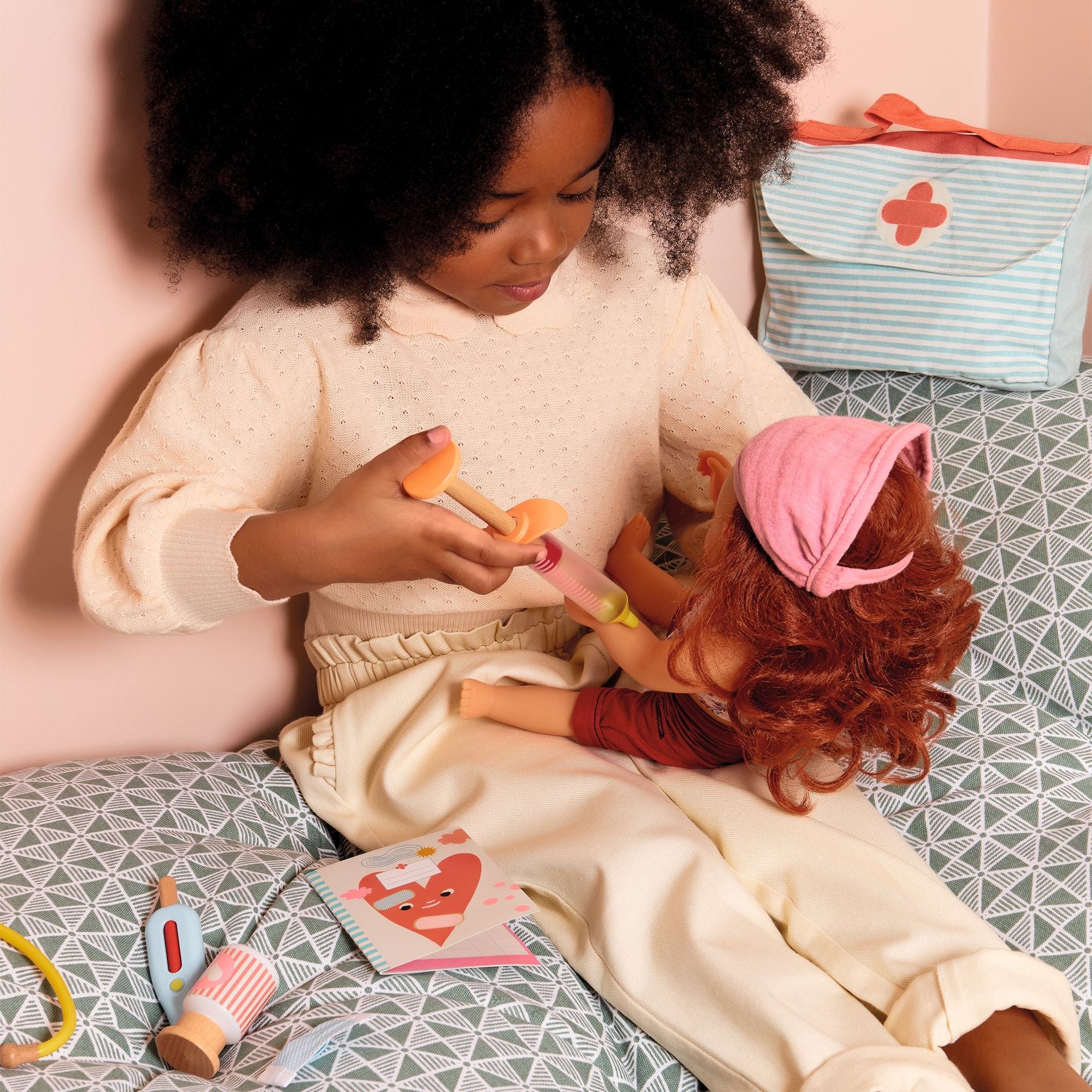 Child playing with a doll on a patterned bed
