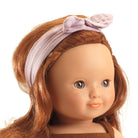Close-up of a doll with red hair and a pink headband on a white background