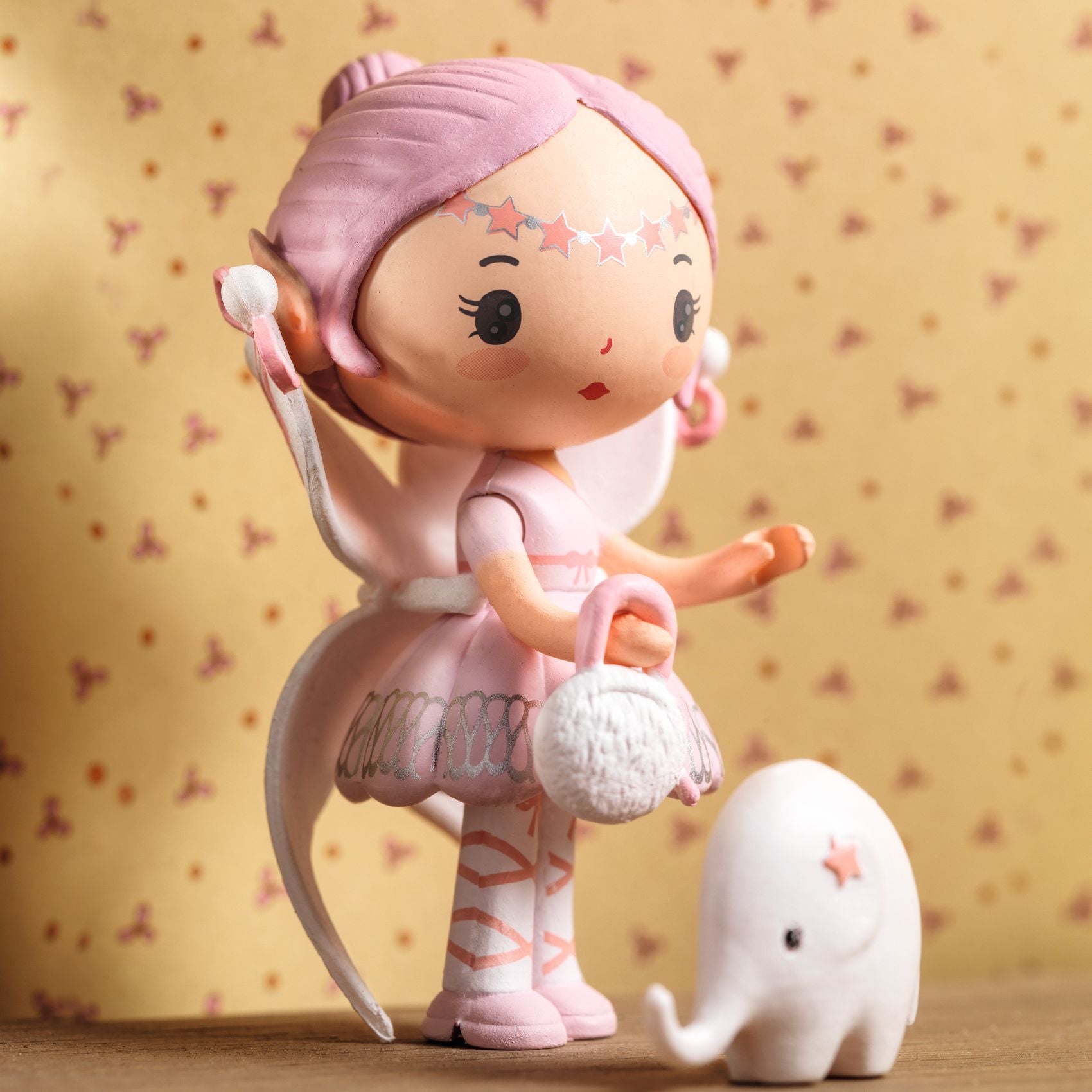 Pink figurine with a small white elephant on a patterned background