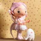 Pink fairy-like figurine with a small white creature on a patterned background