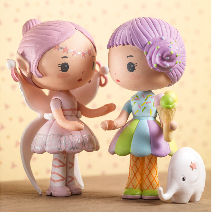 Two animated character figurines with a small elephant toy on a wooden surface.