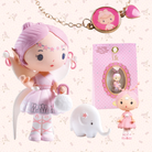 Cute fairy-like doll with pink hair and outfit, accompanied by a small elephant toy and packaging on a decorative background.