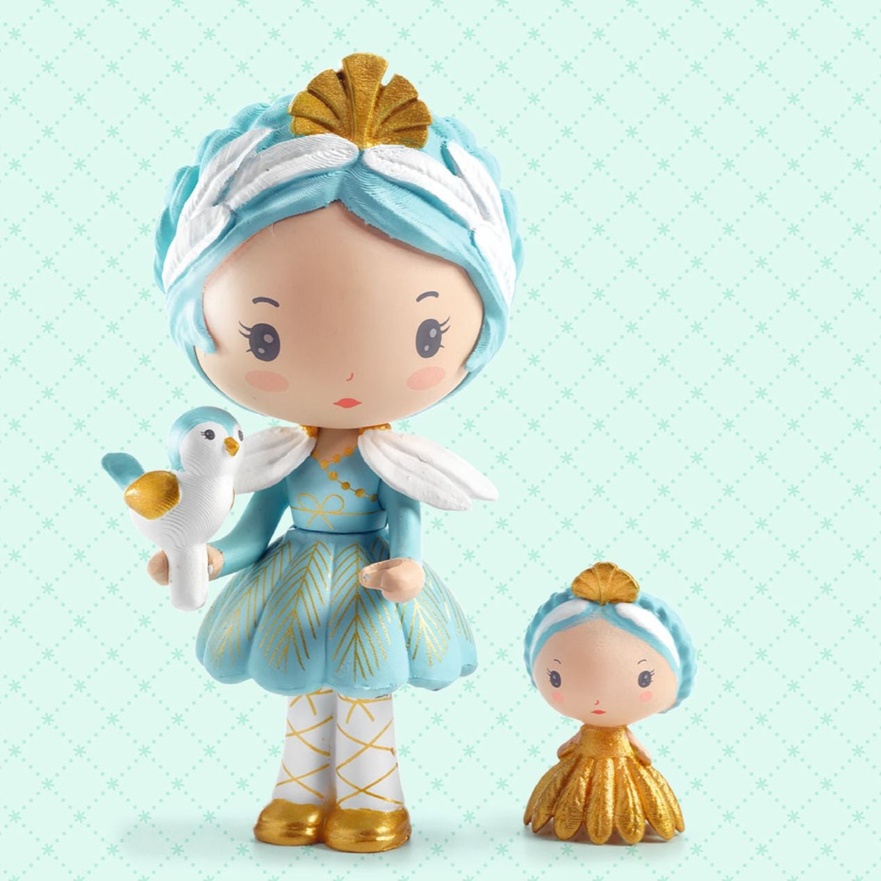 Two small figurines with blue and gold attire on a light green background, featuring the brand 'tinyly'.