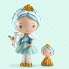 Two small figurines with blue and gold attire on a light green background, featuring the brand 'tinyly'.
