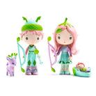 Two characters with green hair and accessories, standing next to a small purple creature and a baby in a green crib.
