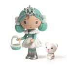 Toy figure of a girl with teal hair and snowflake crown, holding a basket, with a small white teddy bear beside her on a white background.