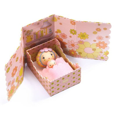 Small figurines in a decorative bed with floral patterns on a white background