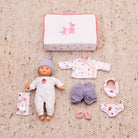 Baby doll with accessories including a suitcase on a beige carpet