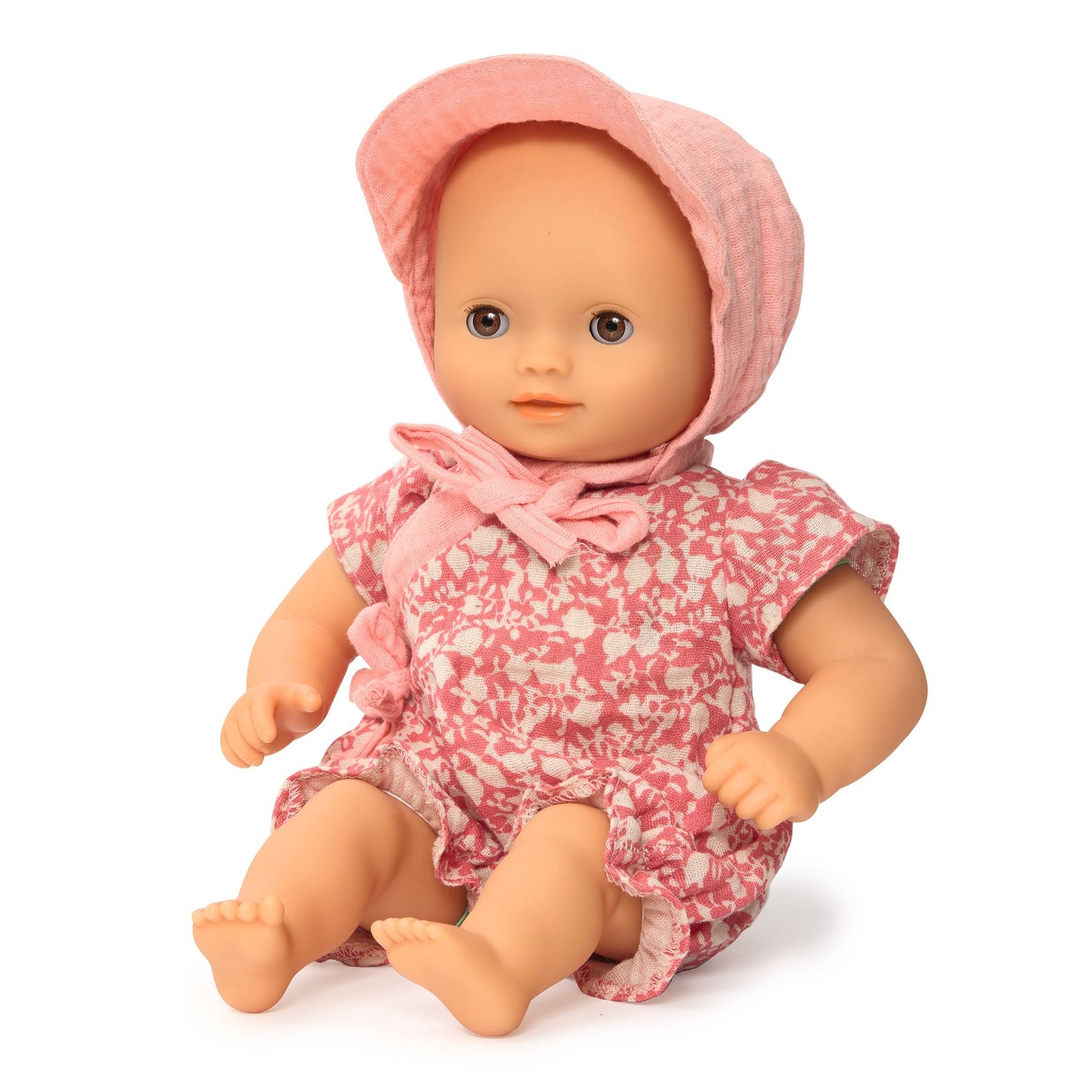 Doll wearing a pink floral dress and bonnet on a white background