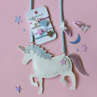Unicorn-shaped hair clip set with decorative clips on a pink background