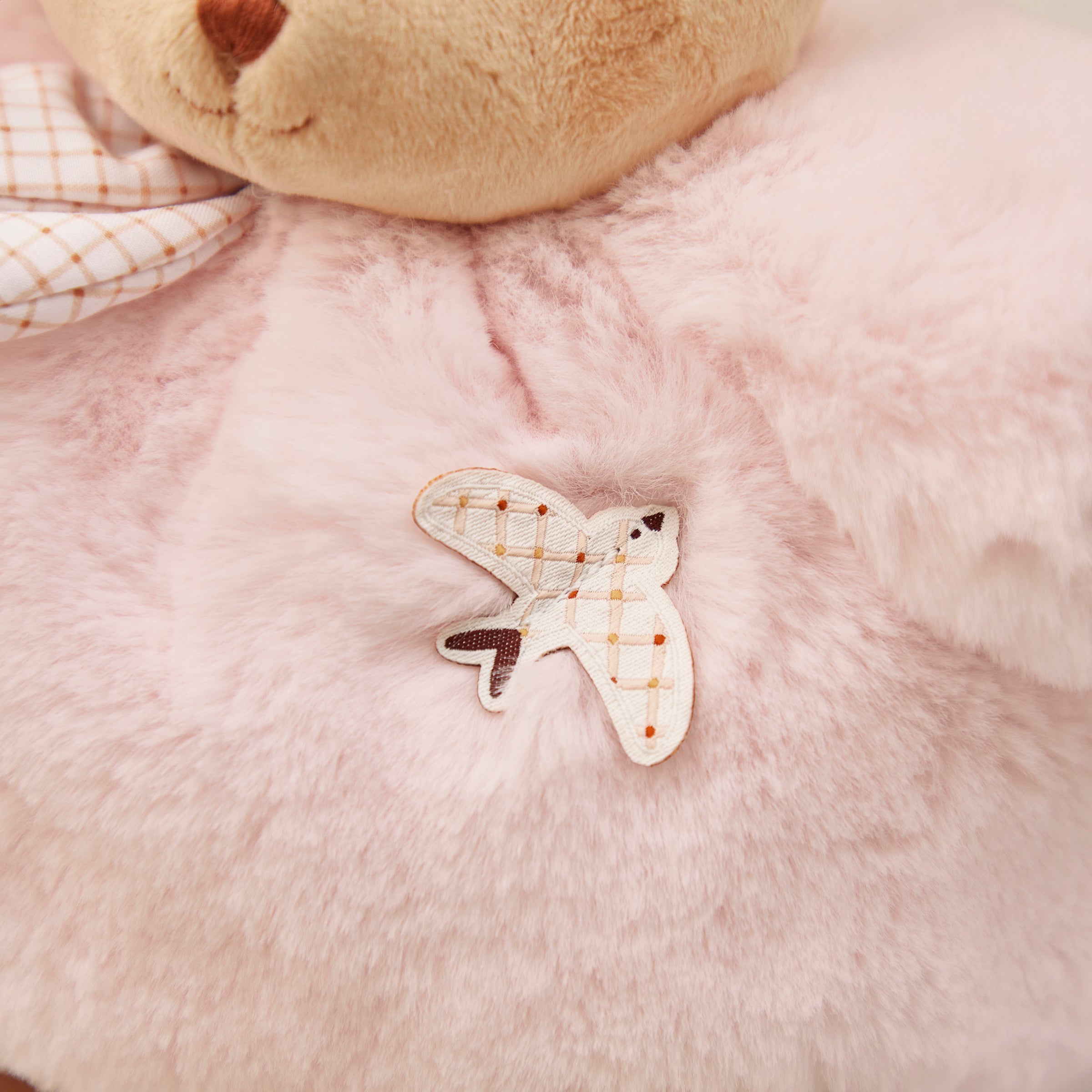Plaid butterfly patch on a soft pink fabric background
