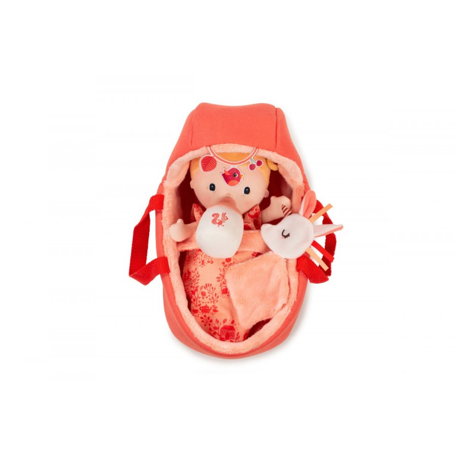Plush baby doll in a red crib on a white background