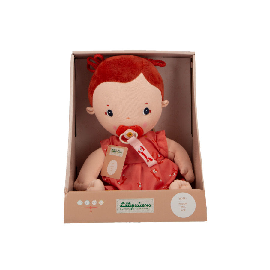 Stuffed toy with red hair and outfit in a cardboard box on a white background