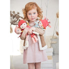 Child holding dolls with a neutral background