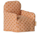 A small fabric armchair with a warm beige base and brown polka dots, photographed on a plain white background. A small fabric brand tag is visible on the right side.