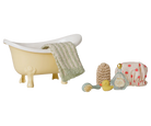 A miniature dollhouse-style bathroom set featuring a small cream bathtub with a green-and-white striped towel draped over the side, plus matching accessories including a yellow rubber duck, beige scrubber, blue brush, and a pink polka-dot bath mat.