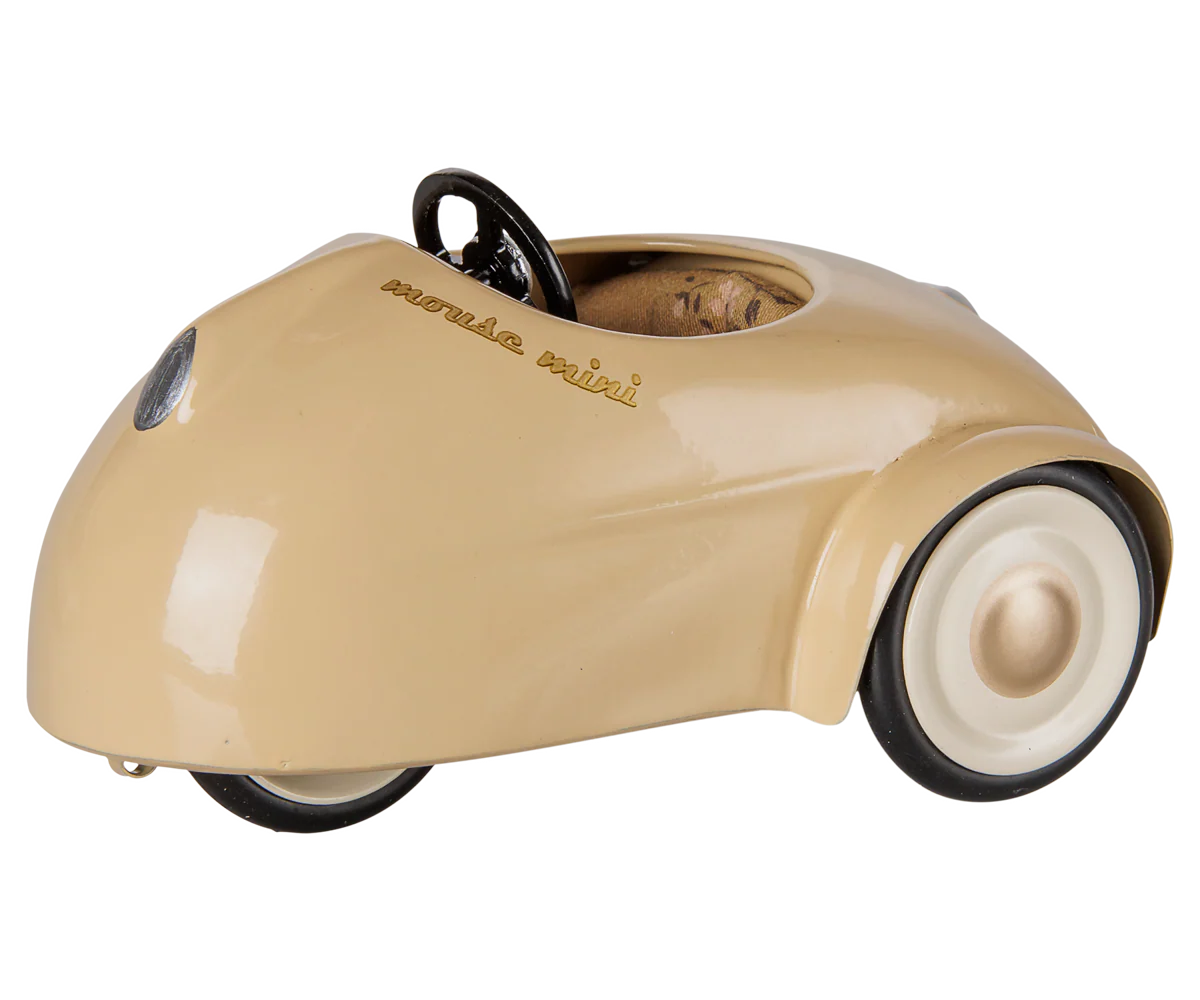 A vintage-style toy car in a glossy beige finish with black wheels, white sidewalls, and a black steering wheel. The word 'Mazda' is embossed on the side panel.