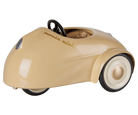 A vintage-style toy car in a glossy beige finish with black wheels, white sidewalls, and a black steering wheel. The word 'Mazda' is embossed on the side panel.