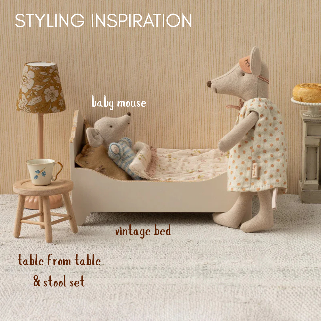 dolls house room setup with vintage bed, table, and lamp, featuring labeled items.