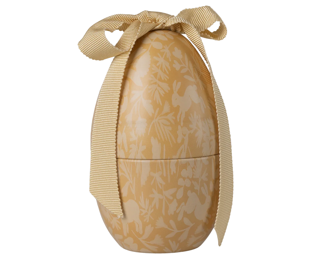 Decorative egg-shaped container with floral pattern and gold ribbon on a white background