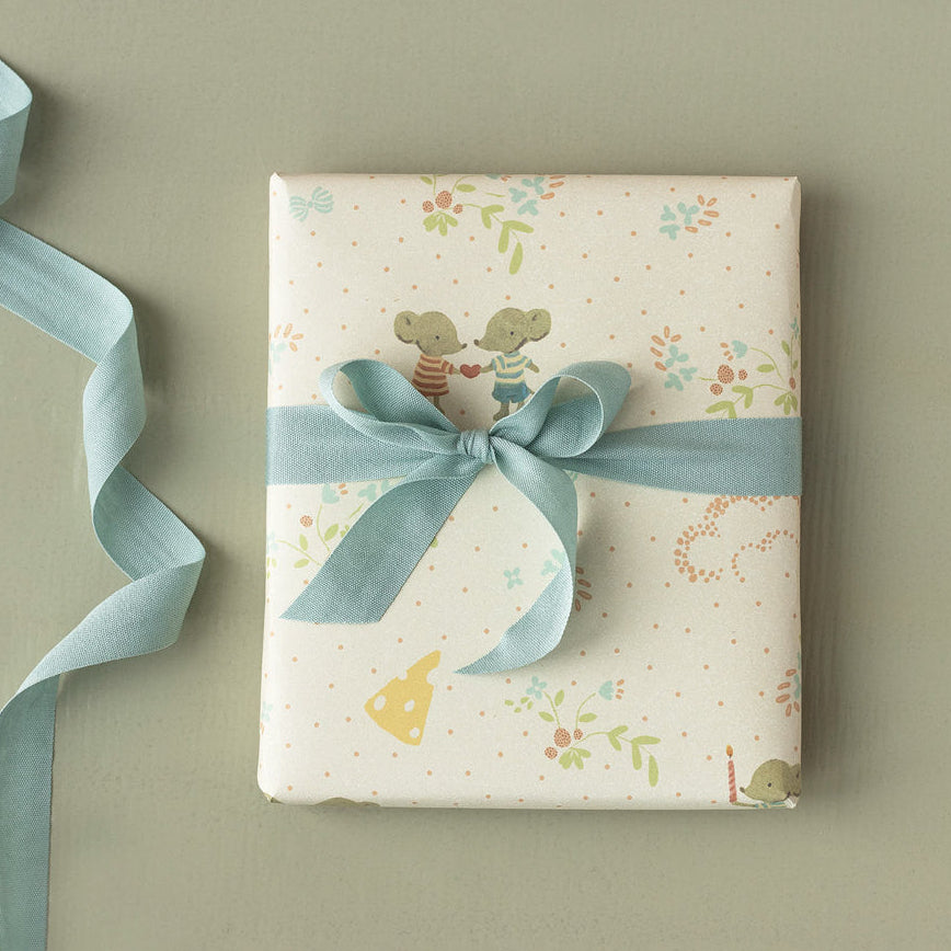 Gift box with floral pattern and blue ribbon on a beige background