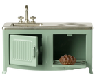 Miniature green kitchen set with sink and stove on a white background