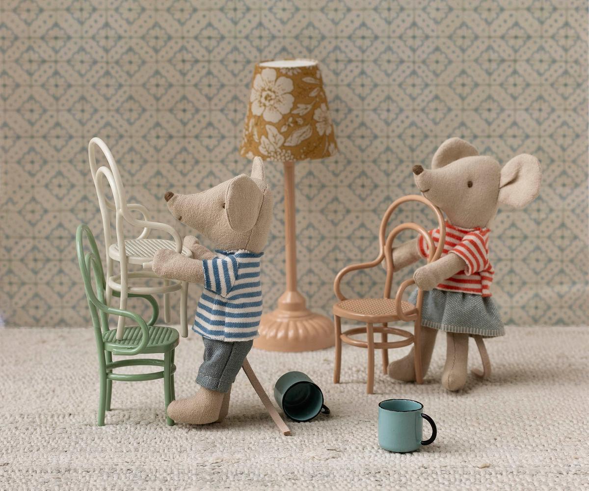 Two toy mice in a miniature room with furniture and decor.