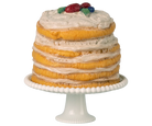 Layered cake with white frosting and fruit on top, placed on a white cake stand.