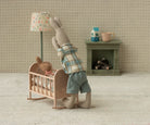 Miniature scene with a rabbit standing next to a baby crib in a cozy room.
