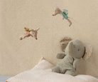 Children's room with stuffed animals on a bed against a patterned wall.