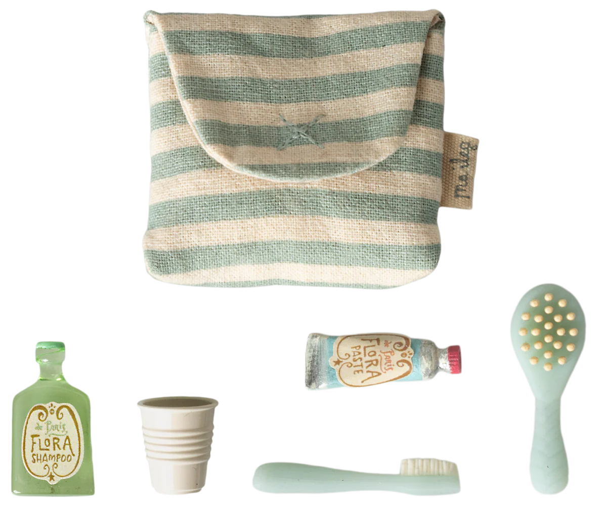 Set of eco-friendly products including a striped pouch, bottle, cup, tube, and brush on a white background.